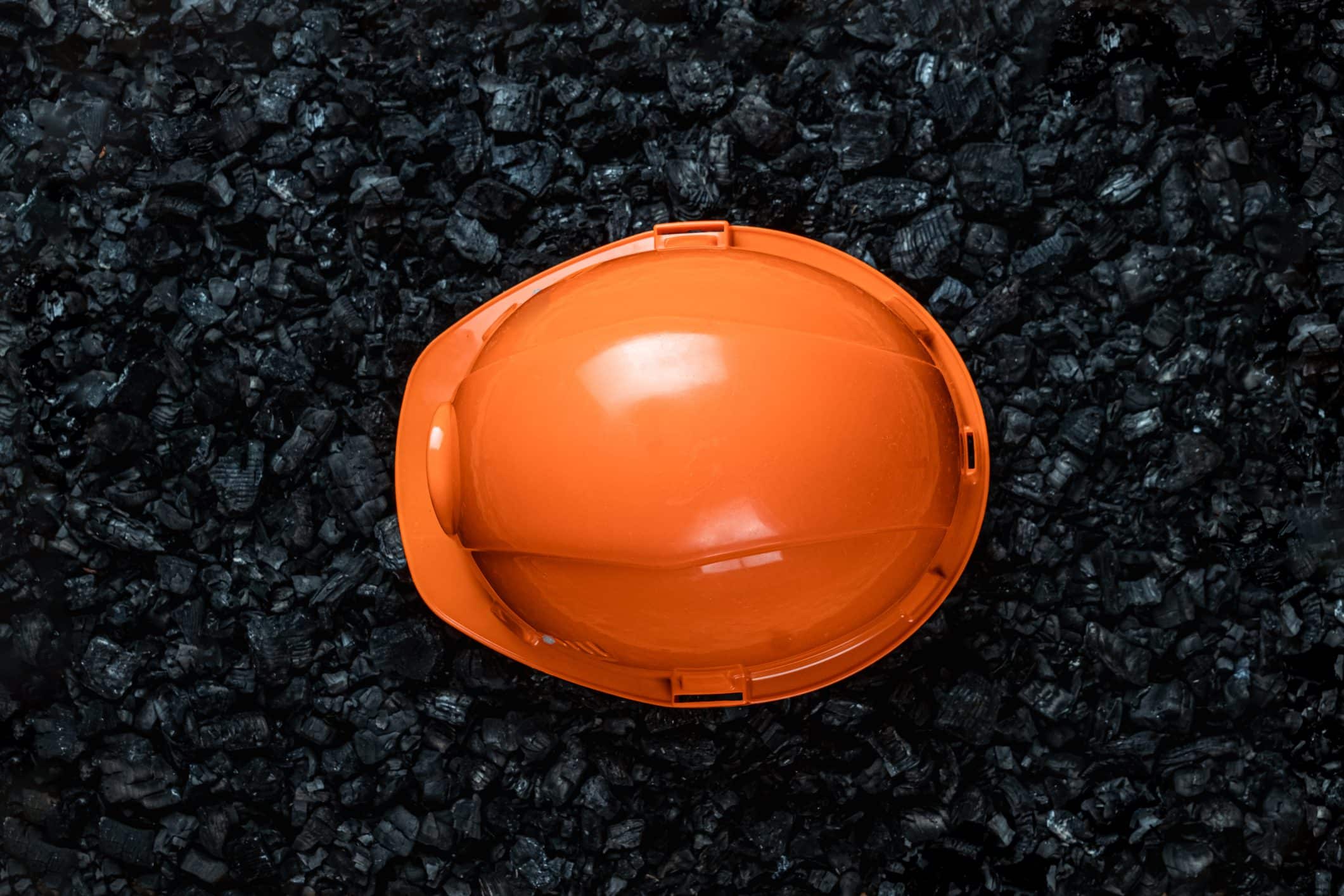 Orange miner helmet on gravel.